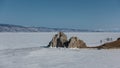 A two-headed rock devoid of vegetation rises on the frozen lake.