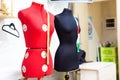 Two headless female mannequins with centimeter tapes in tailors shop, selective focus.