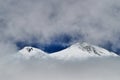 Two heads of Elbrus mountain viewed through fog and clouds Royalty Free Stock Photo