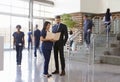 Two healthcare workers talk in the lobby of a busy hospital Royalty Free Stock Photo