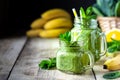 Two healthy green smoothies with spinach, banana, orange and mint in glass jar and ingredients. Detox, diet, healthy, vegetarian Royalty Free Stock Photo