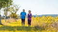 Two healthy senior people jogging on a country road in summer