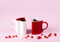 Two heart shape mugs on pink background