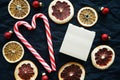 Two heart-shaped candycanes next to dried citrus fruits, Christmas tree decorations and a notepad for notes