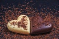 Two heart-shaped chocolates made of milk and white chocolate on the slate board, covered in grated chocolate Royalty Free Stock Photo