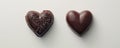 Two heart shaped chocolates placed on a white surface Royalty Free Stock Photo