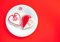 Two heart shaped cookies with a lipstick kiss and a plate on a red background Royalty Free Stock Photo