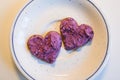 Two heart shaped cookies spread with blueberry curd cream for Valentine\'s Day on plate on white table top view Royalty Free Stock Photo