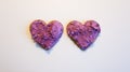 Two heart shaped cookies spread with blueberry curd raw cream for Valentine`s Day on white table surface top view