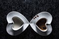 Two heart shaped cups with black coffee and milk pointing to each other, with three coffee beans Royalty Free Stock Photo