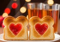 Two heart shaped jam toast slices with drinks and bokeh lights Royalty Free Stock Photo