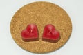 Two heart shaped red candles on round cork hot pad on white background. Royalty Free Stock Photo