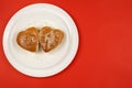 Two heart-shaped sesame burgers on a white plate Top view. The concept of Valentine`s Day.