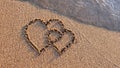 Two hearts drawn on brown sand of paradise beach Royalty Free Stock Photo