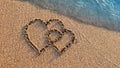 Two hearts drawn on brown sand of paradise beach Royalty Free Stock Photo