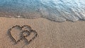 Two hearts drawn on brown sand of paradise beach Royalty Free Stock Photo