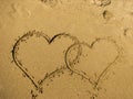 Two hearts drawn on sand of a beach.