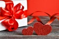 Two hearts with gift box on a wooden background. Couple of different red hearts. Valentine`s day card. Royalty Free Stock Photo