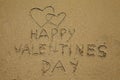 Two hearts and the inscription Happy Valentines Day is drawn on the beach sand. Royalty Free Stock Photo