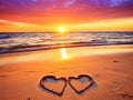 Two hearts made of sand on the beach against a beautiful multicolored sunset sky with clouds Royalty Free Stock Photo