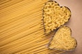 Two hearts of pasta on brown paper background. Heap of raw spaghetti on parchment. Top view. Texture of uncooked macaroni. Traditi Royalty Free Stock Photo