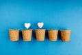 Two hearts are in pots, two pots are occupied, the rest are empty, the background is blue Royalty Free Stock Photo