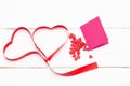 Two hearts of red ribbon with a few small hearts and greeting card on white wooden background. Royalty Free Stock Photo