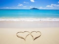 Two hearts on a sandy beach, against a beautiful blue sea with waves and a sky with clouds Royalty Free Stock Photo
