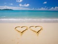 Two hearts on a sandy beach, against a beautiful blue sea with waves and a sky with clouds Royalty Free Stock Photo