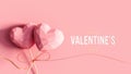 Two hearts on the stick tied with golden bow and Happy Valentine`s Day text on pink background