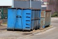 Two heavily used large industrial partially rusted strong blue metal recycling containers left on side of road