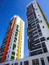 Two high-rise multi-colored apartment complexes on a blue sky background