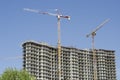 Two high-rise multi-colored cranes next to the new building under construction Royalty Free Stock Photo