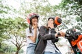 Two high school girls joking while riding a motorbike