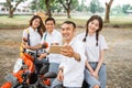 Two high school students selfie while sitting on a motorbike