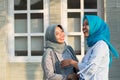 Two hijab women neighbors meet and say hi while smiling and shake hands in front of their house Royalty Free Stock Photo