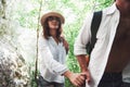 Two hikers with backpacks on the back in nature. Man and woman holding hands while walk on a summer day Royalty Free Stock Photo