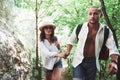 Two hikers with backpacks on the back in nature. Man and woman holding hands while walk on a summer day Royalty Free Stock Photo