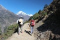 Two hikers with backpacks walks along a mountain trail in Himalayas