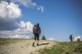 Two hikers follow a path, the blue sky on the horizon. Hiking travel outdoor concept panoramic view