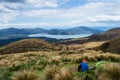 Two hikers looking at view of lake Rotoaira and lake Taupo from Tongariro Alpine Crossing hike with clouds above