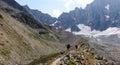 Two hikers and mountain climbers hiking along a glacier moraine