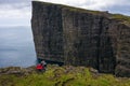Two hikers sitting on the edge of a cliff on Faroe Islands Royalty Free Stock Photo