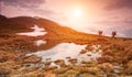 Two hiking in the mountains in beautiful morning at a small lake