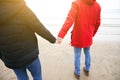 Two hipsters standing on the cold beach. Couple hugging and holding hands. Love story near the ocean. Winter season on the sea. Royalty Free Stock Photo