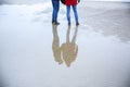 Two hipsters standing on the cold beach. Couple hugging and holding hands. Love story near the ocean. Winter season on the sea. Royalty Free Stock Photo