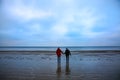 Two hipsters standing on the cold beach. Stylish couple hugging and holding hands. Love story near the ocean. Winter season on the Royalty Free Stock Photo