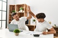 Two hispanic men couple high five hands raised up using laptop working at home