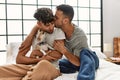 Two hispanic men couple kissing and hugging each other sitting on bed with chihuahua at bedroom Royalty Free Stock Photo