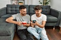 Two hispanic men couple using smartphone and drinking coffee at home Royalty Free Stock Photo